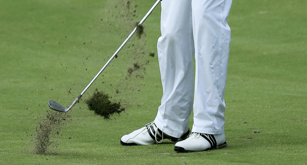 Golfer hitting a pure iron shot with ball first contact and divot after.