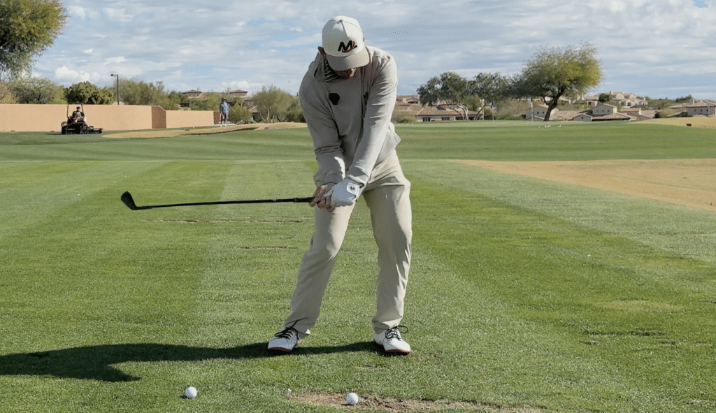 Milo Lines hitting out of a divot to show good stance width, weight transfer onto lead foot, and front foot posting up to help move low point forward.